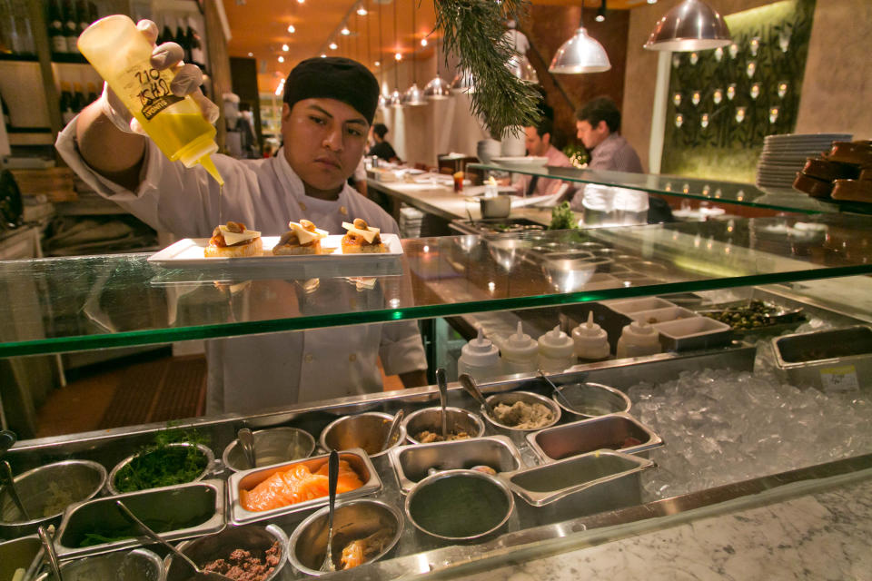 This Dec. 5, 2013 photo shows a dish being prepped at Fig & Olive restaurant, near New York's Rockefeller Center. Rockefeller Center is crowded at Christmastime thanks to the famous tree, the skating rink and the show at Radio City Music Hall, but visitors can choose from a variety of places to eat in the area, from ethnic food and street carts to sit-down dining. (AP Photo/Richard Drew)