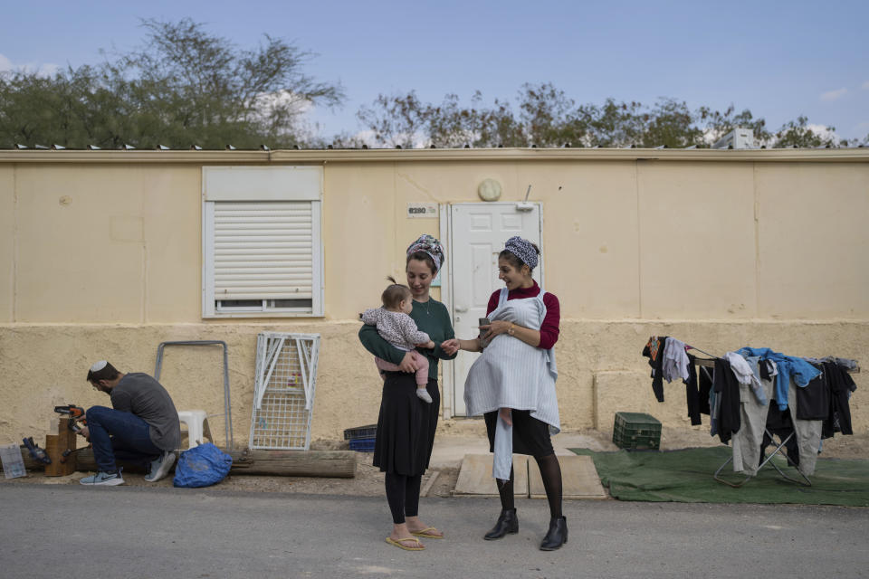 Jewish settlers and their children stand outside their home at the West Bank outpost of Beit Hogla, Wednesday, Feb. 15, 2023. Israel's new ultranationalist government declared last week that it would legalize 10 unauthorized outposts in the occupied West Bank. The rare move intensified the country's defiance of international pressure and opened an aggressive new front of Israeli expansion into the West Bank, which Israel captured in the 1967 Mideast war. (AP Photo/Ohad Zwigenberg)