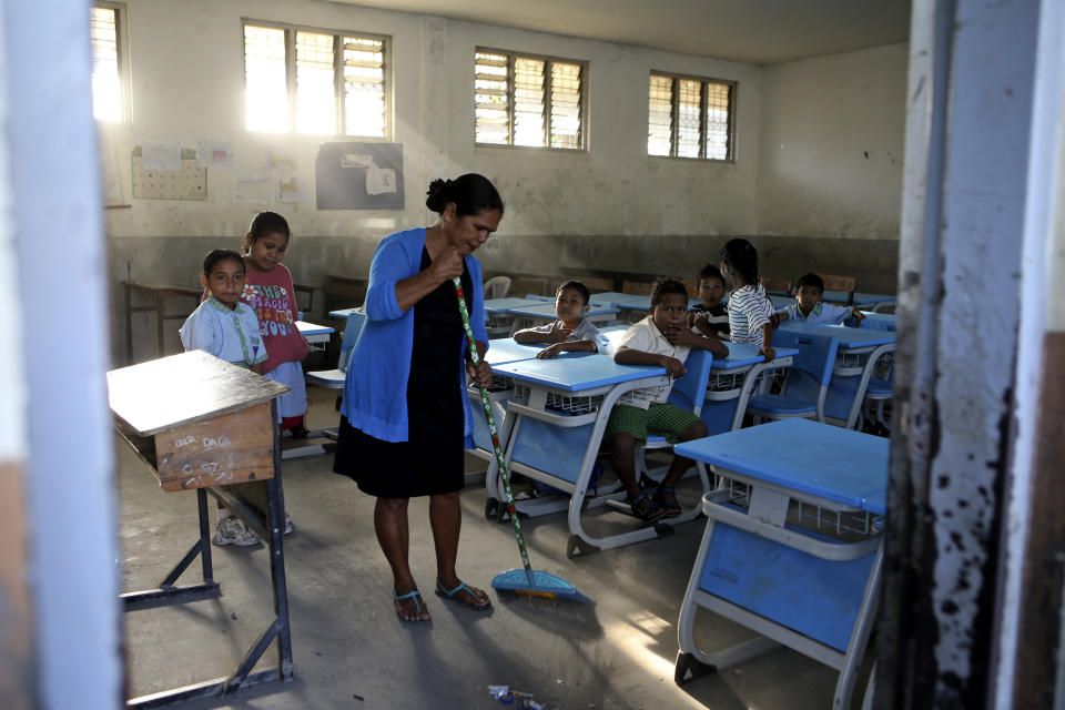 A school teacher sweeps the floor of a classroom before the start of classes in Dili, East Timor, Thursday, Sept. 5, 2024. (AP Photo/Firdia Lisnawati)