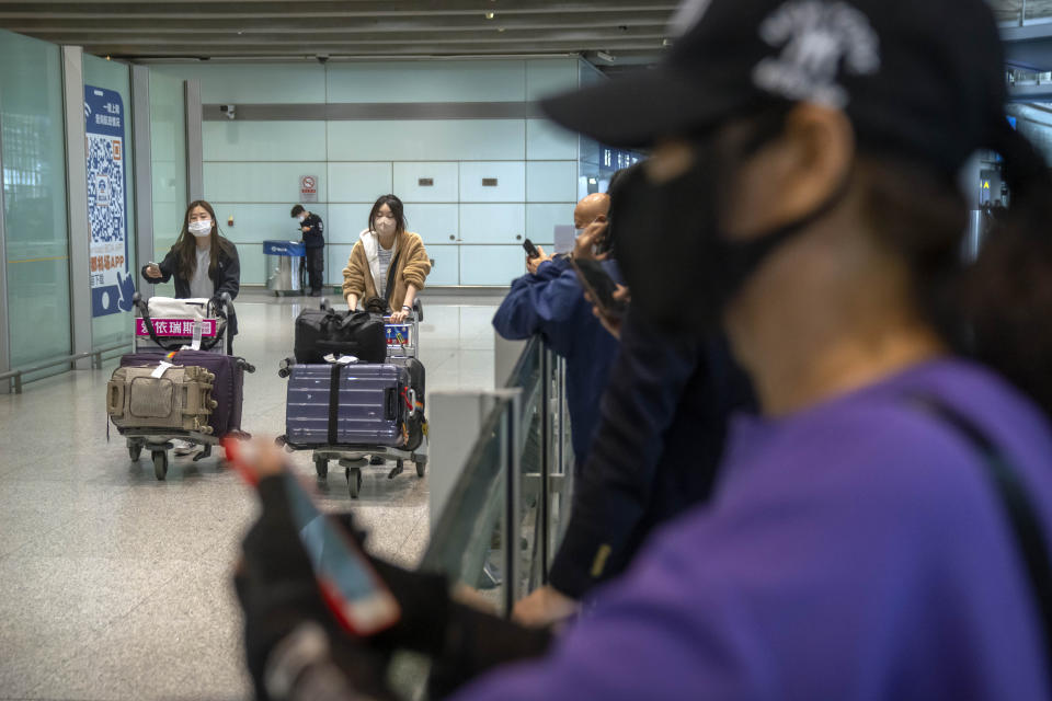 Travelers wearing face masks walk through the international flight arrivals area at Beijing Capital International Airport in Beijing, Wednesday, April 26, 2023. Travelers entering China will no longer need to provide a negative PCR test result starting from Saturday, in another easing of China's "zero-COVID" policies. (AP Photo/Mark Schiefelbein)