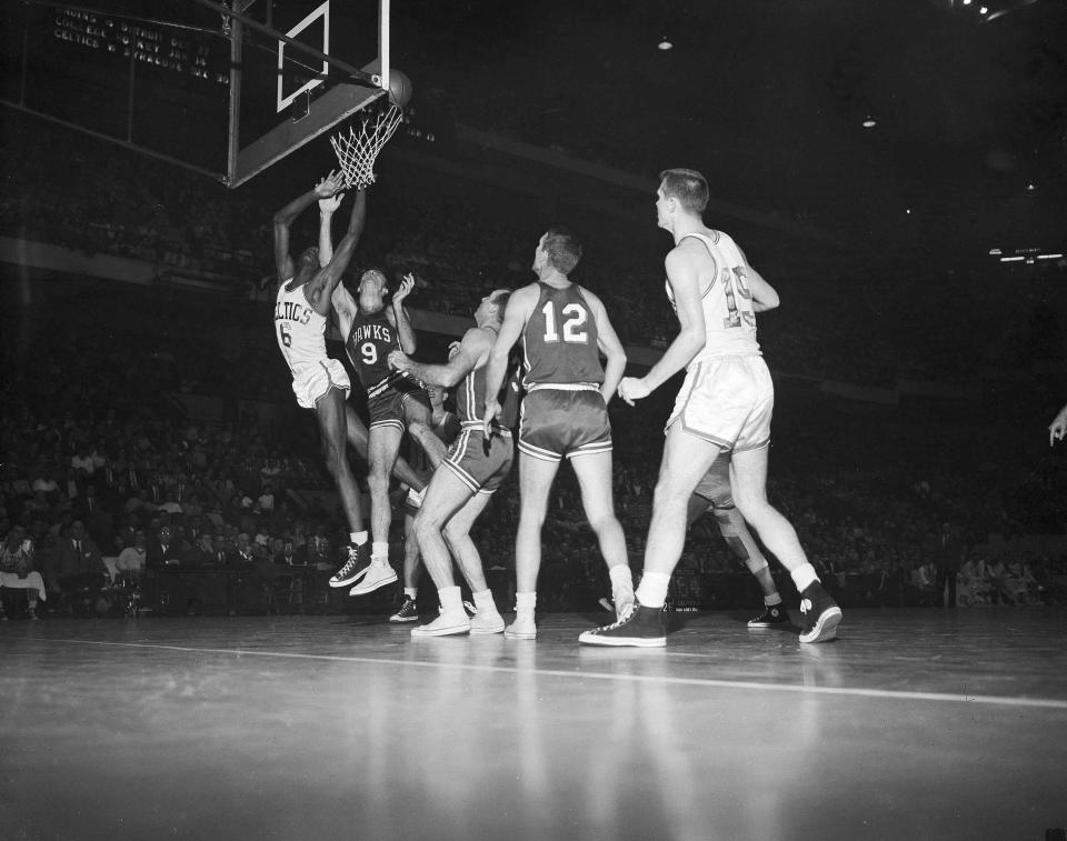 Bill Russell (6), the most publicized player to come out of college basketball in years, is fouled by Bob Pettit (9) of the St. Louis Hawks, as Russell made his professional debut with the Boston Celtics in Boston. (AP Photo/J. Walter Green)