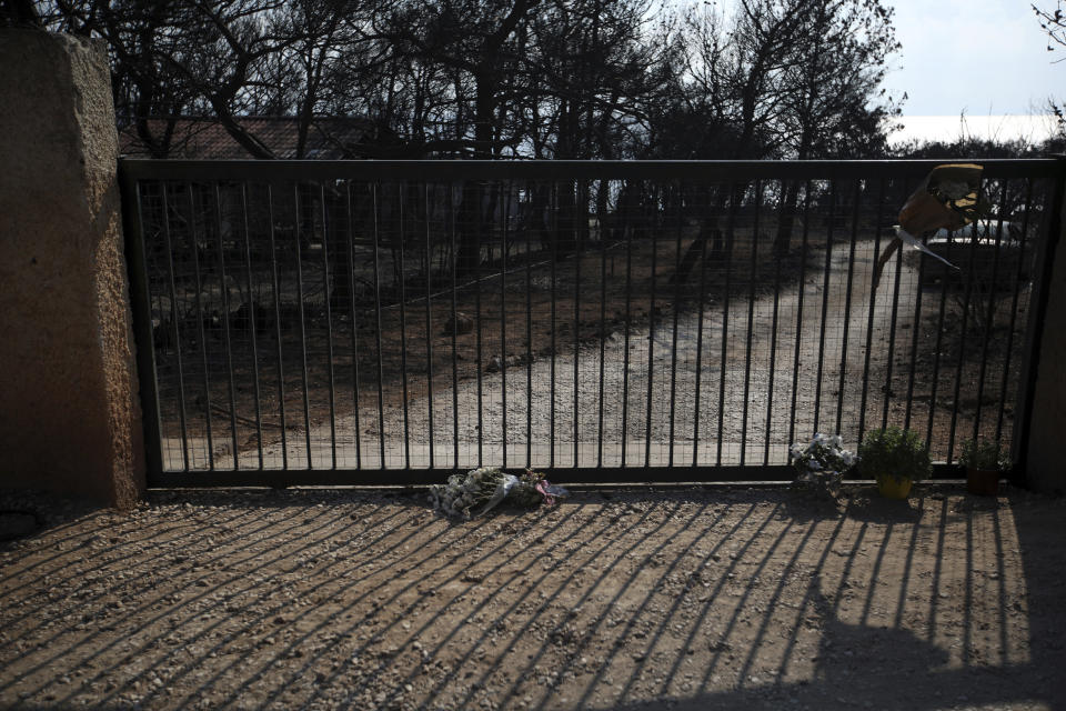 Flowers are placed outside a burnt compound in Mati, east of Athens, Wednesday, Aug. 1, 2018, where over 20 people were found dead during the wildfire. The bodies of 76 people killed by Greece's deadliest wildfire in decades have been identified, authorities said Tuesday, as forensic experts kept working to identify more remains recovered from the charred resort area. (AP Photo/Thanassis Stavrakis)