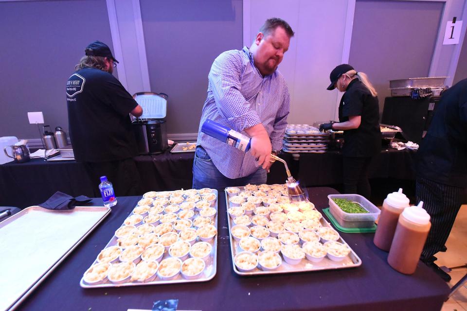 James Smith helps to prepare Fork-N-Cork’s Lobster Mac & Cheese with truffle hot sauce during the Make-A-Wish Eastern North Carolina‘s 2020 Wish Upon a Chef event Thursday Jan. 30, 2020 at UNCW’s Burney Center. [KEN BLEVINS/STARNEWS]