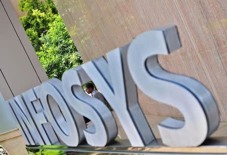 An employee is seen behind an Infosys logo at the company's campus in the southern Indian city of Bangalore September 23, 2014. REUTERS/Abhishek Chinnappa