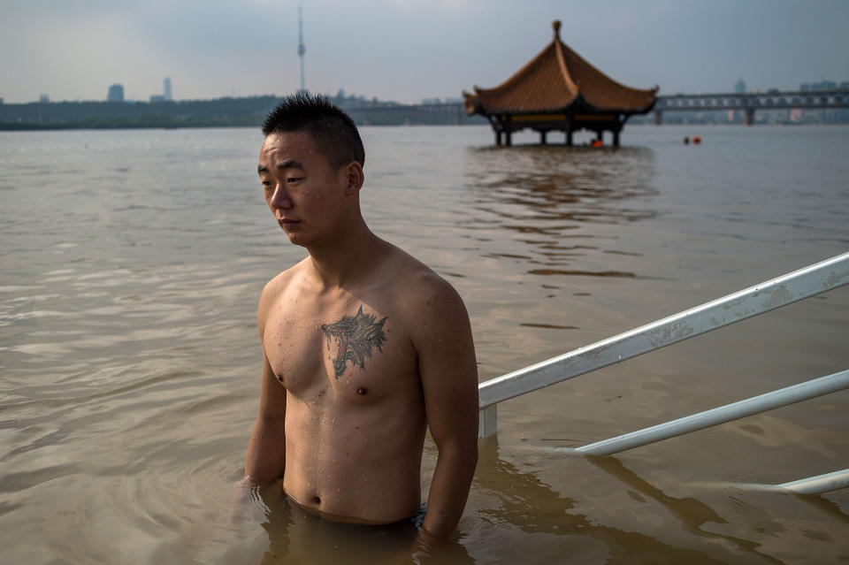 <p>A man stands in the Yangtze River along the River Beach Park in Wuhan, Hubei Province, China on July 3, 2017, after heavy rains caused the water levels to rise. (Photo: STR/AFP/Getty Images) </p>