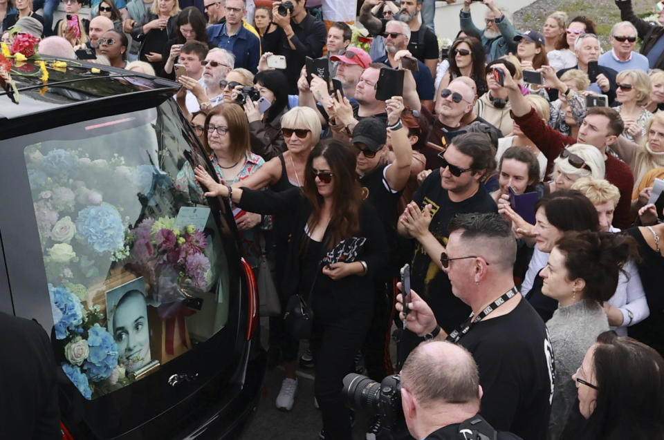 Fans de Sinéad O'Connor rodean su carroza fúnebre en su ciudad natal de Bray, en el condado de Wicklow, Irlanda el martes 8 de agosto de 2023. (Liam McBurney/PA vía AP)