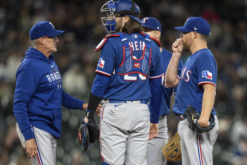 Texas Rangers pitching coach Mike Maddux, left, meets at the mound with catcher Jonah Heim and relief pitcher Ian Kennedy, right, during the eighth inning of the team's baseball game against the Seattle Mariners on Tuesday, May 9, 2023, in Seattle. (AP Photo/Stephen Brashear)