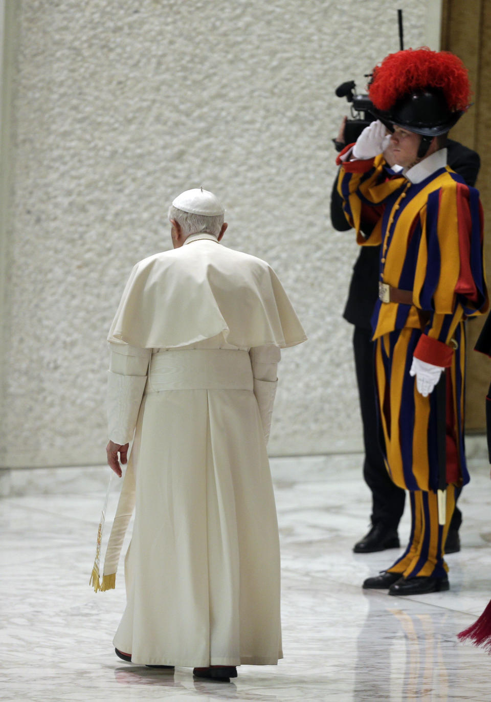 FILE - Pope Benedict XVI walks past a Swiss guard on Feb. 13, 2013, as he leaves at the end of his weekly general audience, his first public appearance since dropping the bombshell announcement of his resignation, in the Paul VI Hall at the Vatican. Benedict chose Feb. 11, 2013 -- a Vatican holiday, with a routine audience with his cardinals -- to make the historic announcement in Latin that he would become the first pope since Gregory XII in 1415 to resign. Benedict, the German theologian who will be remembered as the first pope in 600 years to resign, has died, the Vatican announced Saturday Dec. 31, 2022. He was 95. (AP Photo/Alessandra Tarantino, File)