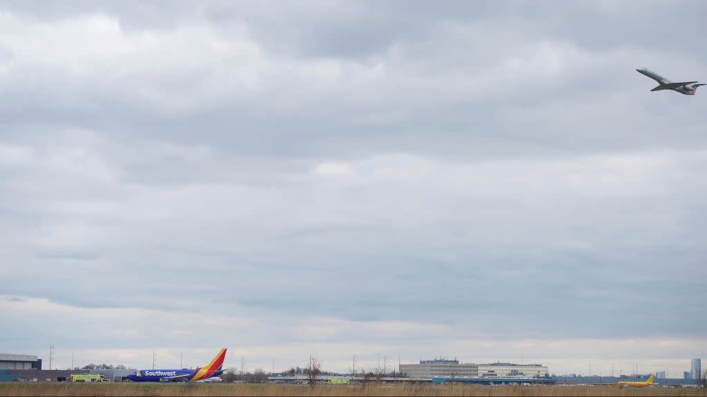 A plane departs as emergency personnel monitor the damaged engine of Southwest Airlines Flight 1380, which diverted to the Philadelphia International Airport this morning, in Philadelphia, Pennsylvania