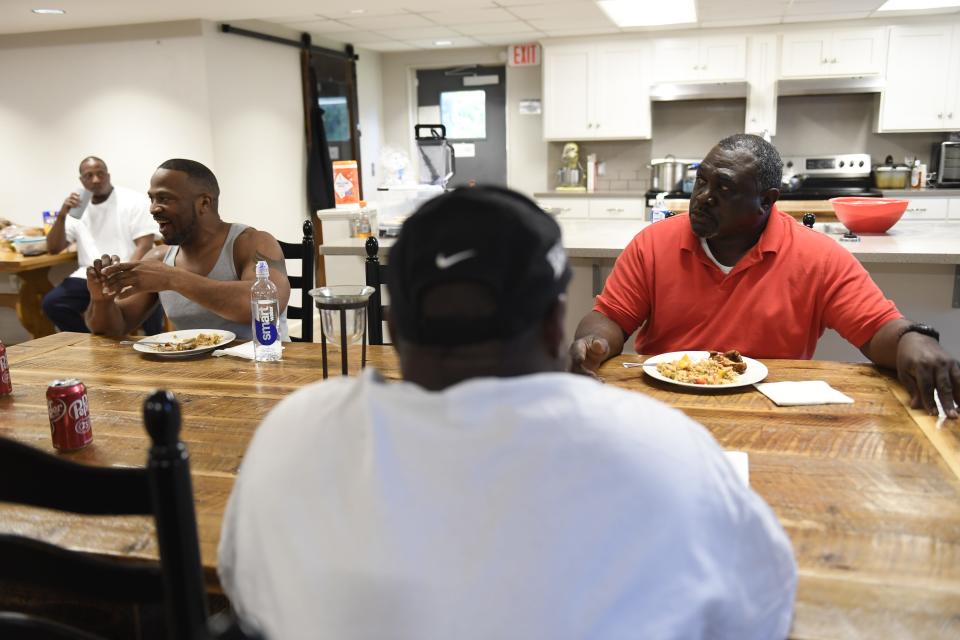 Zane Gray, left, and Henry Thomas, right, Soteria House residents, eat dinner with the rest of the residents in the house on Monday, April 10, 2023.