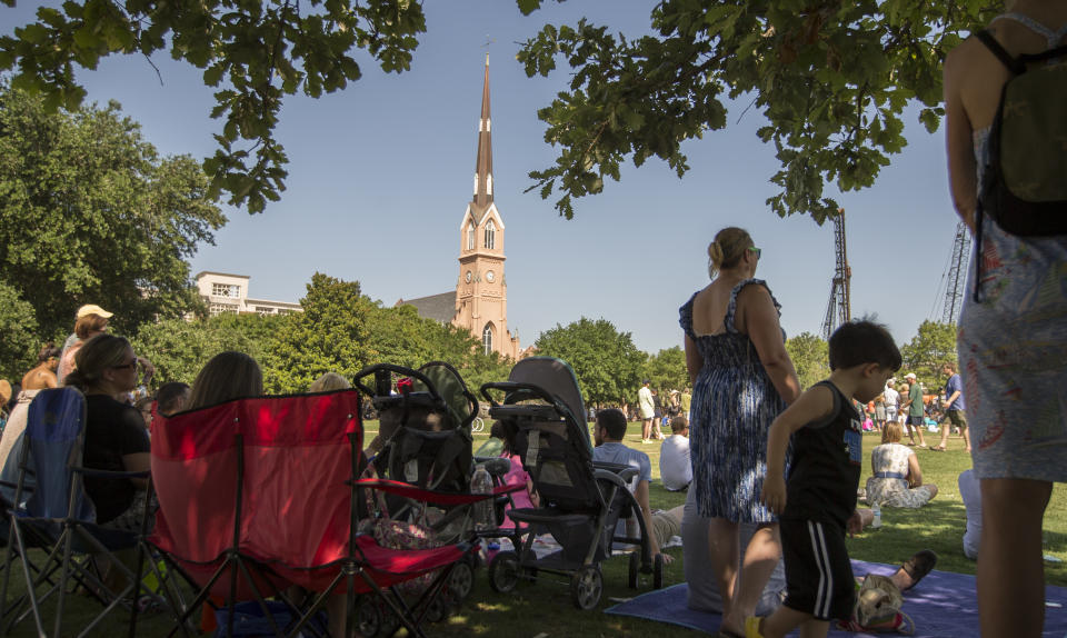 People gather on Marion Square near the St. Matthew's Lutheran Church, center, as churches across the city rang their bells in a show of solidarity with Emanuel A.M.E. Church, Sunday, June 21, 2015, in Charleston, S.C., four days after a mass shooting at Emanuel claimed the lives of its pastor and eight others. (AP Photo/Stephen B. Morton)