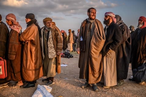 Men suspected of being Isil fighters wait to be searched by members of the Kurdish-led Syrian Democratic Forces (SDF) after leaving the group's last holdout of Baghouz - Credit: AFP