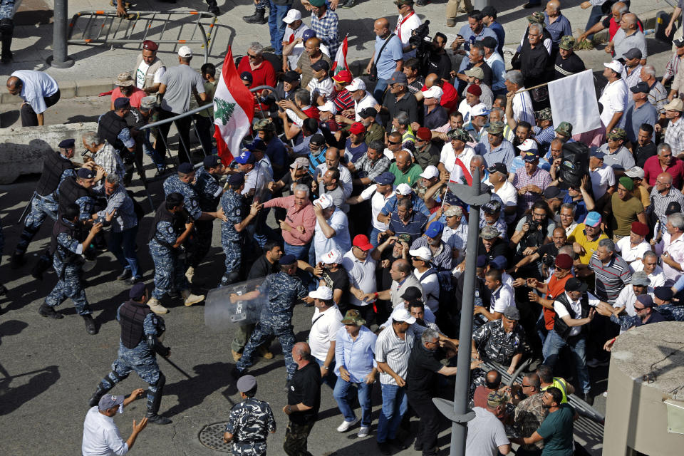 Security forces clash with retired army officers as they try to advance toward the Government House in Beirut, Lebanon, Monday, May 20, 2019, as the government faces a looming fiscal crisis. Over one hundred protesters gathered Monday in downtown Beirut shouting "Thieves, thieves!" as the Cabinet met for its 16th session to reach agreement on controversial budget cuts. (AP Photo/Bilal Hussein)