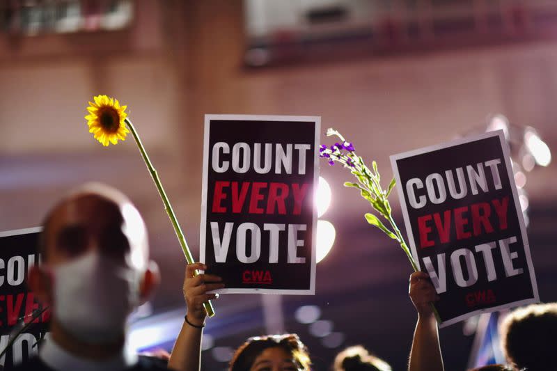 Activists hold up flowers and signs stating "COUNT EVERY VOTE" across the street from where votes are still being counted, two days after the 2020 U.S. presidential election, in Philadelphia