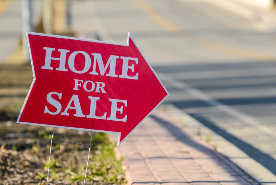 A home for sale sign pointing directing people to a house for sale