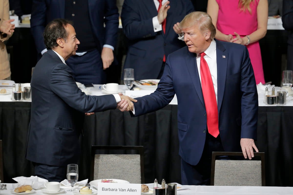 Donald Trump shook hands with John Paulson during a meeting of the Economic Club of New York in November 2019. Mr Paulson is hosting a fundraiser for the Trump campaign on Saturday (AP)