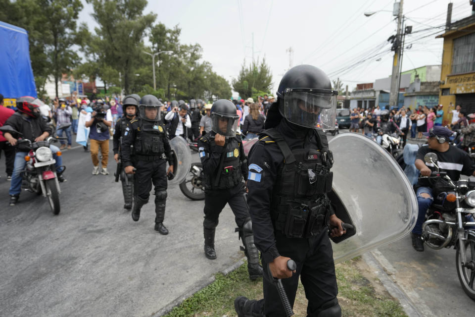 Police in riot gear march on a highway blocked by demonstrators during a national strike, in Guatemala City, Tuesday, Oct. 10, 2023. People are protesting to support President-elect Bernardo Arévalo after Guatemala's highest court upheld a move by prosecutors to suspend his political party over alleged voter registration fraud. (AP Photo/Moises Castillo)