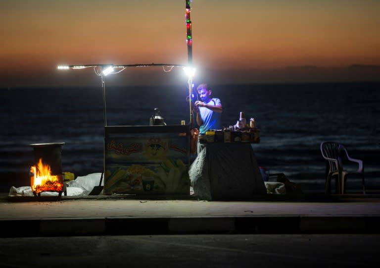 This file photo taken on June 11, 2017 shows a Palestinian street vendor standing behind his stall in front of the beach in Gaza City during a power outage