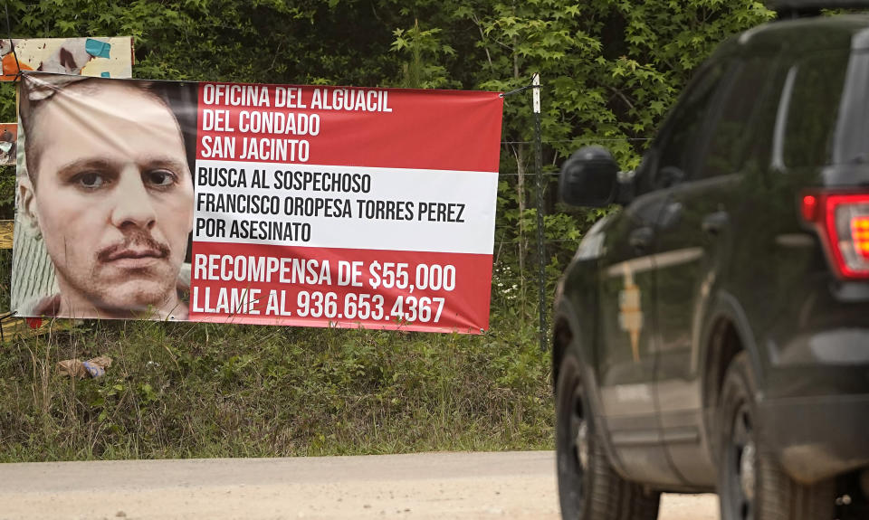 A state trooper vehicle passes a posted wanted sign for a mass shooting suspect Tuesday, May 2, 2023, in the neighborhood where the shooting occurred Friday, in Cleveland, Texas. The search for the suspected gunman who allegedly shot five of his neighbors, including a child, after they asked him to stop firing off rounds in his yard stretched into a fourth day Tuesday. (AP Photo/David J. Phillip)