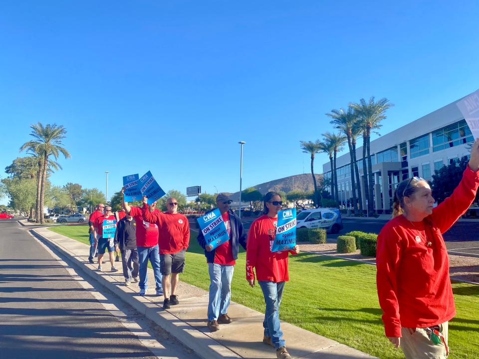 Employees of Maximus and the Communications Workers of America hold up signs outside of the Maximus location in Phoenix on Nov. 9, 2023.