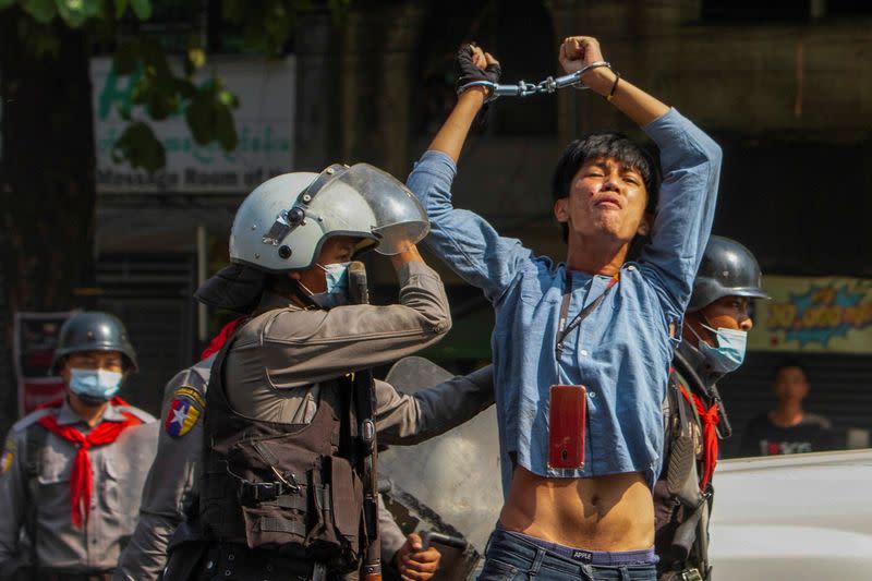 A pro-democracy protester is detained by riot police officers during a rally against the military coup in Yangon