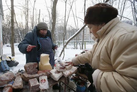 A woman points at a cut of meat as a street vendor sells food in the yard of an apartment building in Moscow, January 26, 2015. REUTERS/Maxim Zmeyev