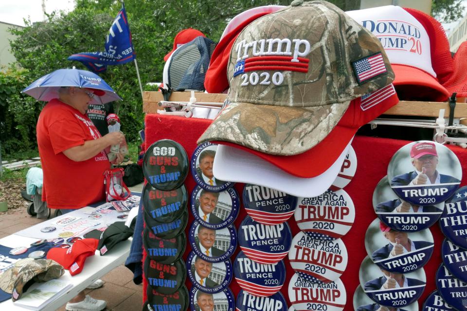 People look over Trump merchandise for sale before the rally in which he announced his 2020 candidacy in Orlando, Fla., on June 18. 