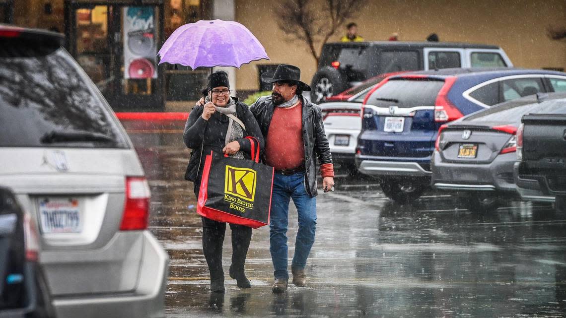 A couple walks through the Fashion Fair mall parking lot to their car as the rain continues to fall on a wet Tuesday afternoon, Dec. 27, 2022.