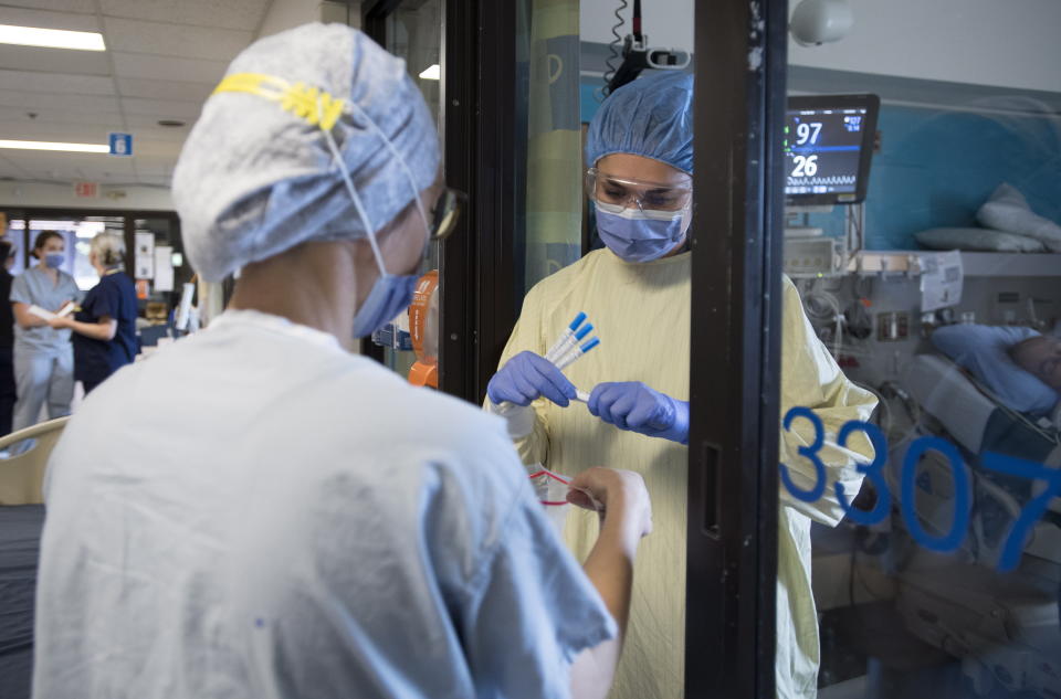 In this Tuesday, April 21, 2020 photo, nurses collect samples from a possible COVID-19 patient in the COVID-19 intensive care unit at St. Paul's hospital in downtown Vancouver, British Columbia. (Jonathan Hayward/The Canadian Press via AP)