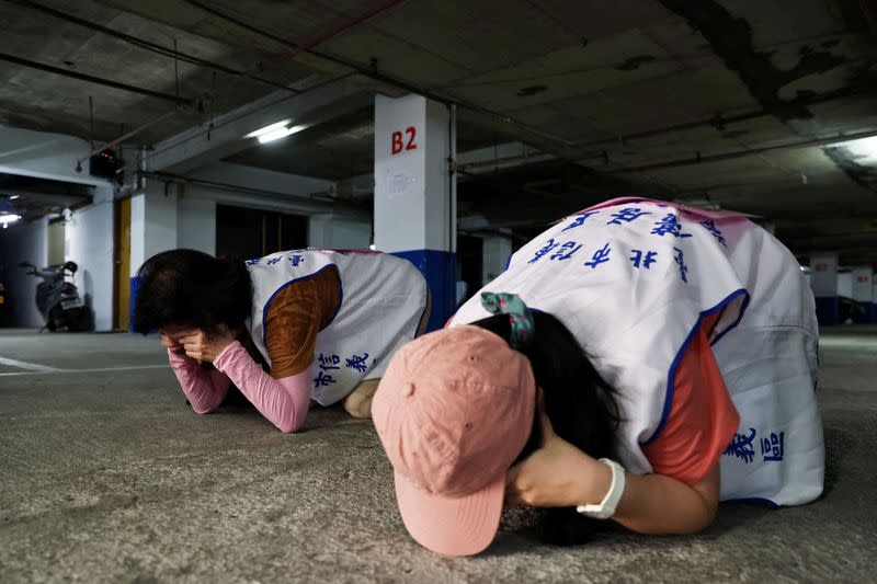 FILE PHOTO: People demonstrate taking shelter during a drill at a basement parking lot in Taipei