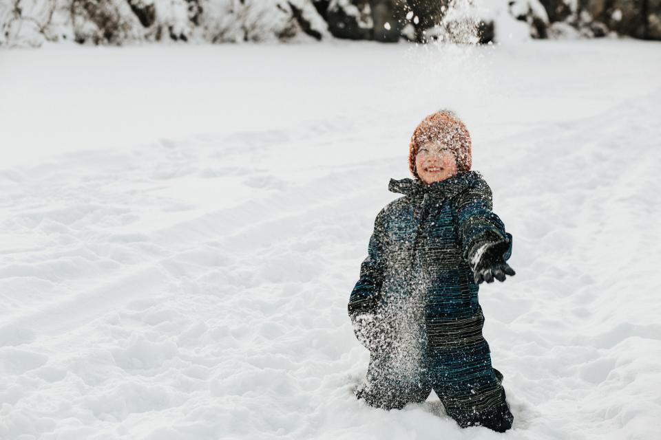 Little boy plays in snow.