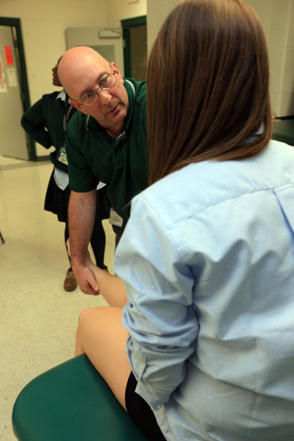 Former Archmere athletic trainer Jim Malseed examines an injured player.