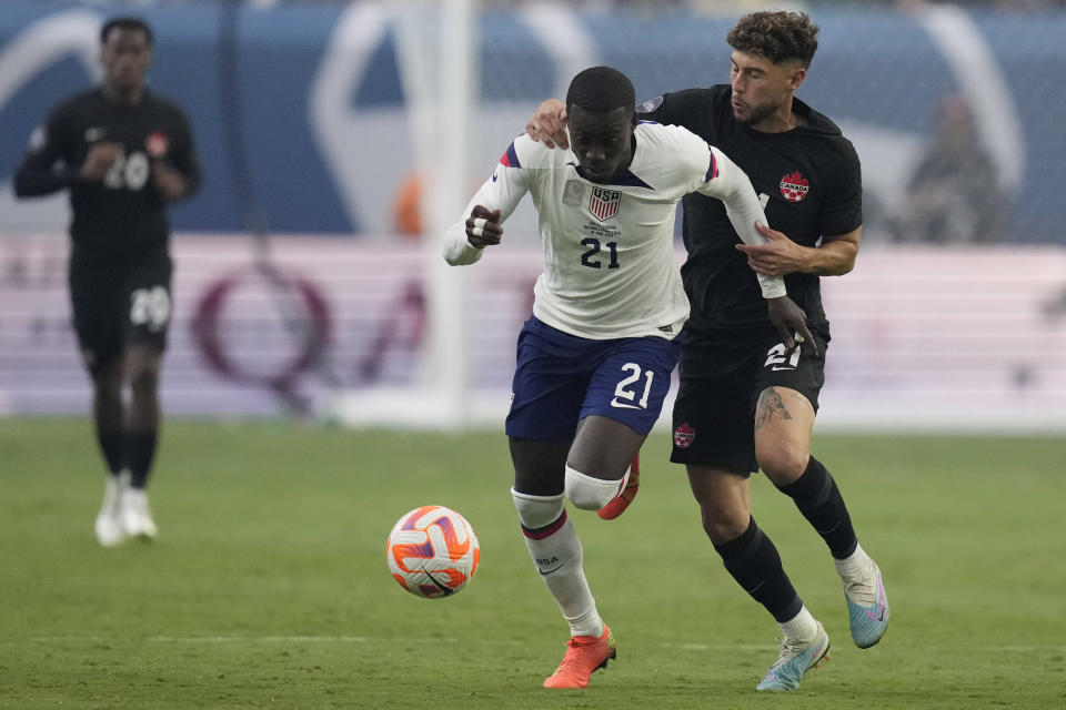 Jonathan Osorio, of Canada, right, grabs Timothy Weah of the United States during the first half of a CONCACAF Nations League final match Sunday, June 18, 2023, in Las Vegas. (AP Photo/John Locher)