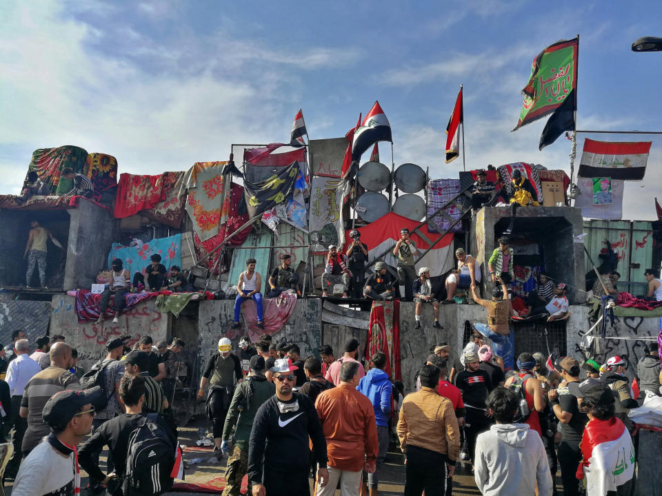 Anti-government protesters stand on barriers set up by security forces to close a bridge leading to the Green Zone government areas during ongoing anti-government protests in Baghdad, Iraq, Thursday, Nov. 7, 2019. (AP Photo/Khalid Mohammed)