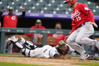 Colorado Rockies catcher Dom Nunez, left, reaches out to recover the ball after a wild pitch from reliever Jordan Sheffield (not shown) allowed Cincinnati Reds' Nick Senzel, right, to score from third base in the ninth inning of a baseball game Sunday, May 16, 2021, in Denver. (AP Photo/David Zalubowski)