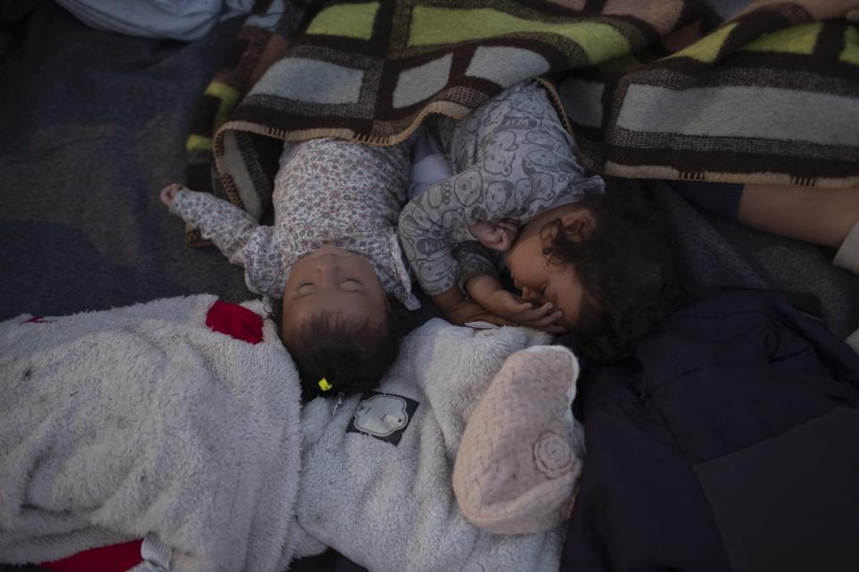 Migrants sleep on a road leading from Moria to the capital of Mytilene, on the northeastern island of Lesbos, Greece, Thursday, Sept. 17, 2020. Greek police are moving hundreds of migrants to an army-built camp on the island of Lesbos Thursday after a fire destroyed an overcrowded facility, leaving them homeless for days. (AP Photo/Petros Giannakouris)