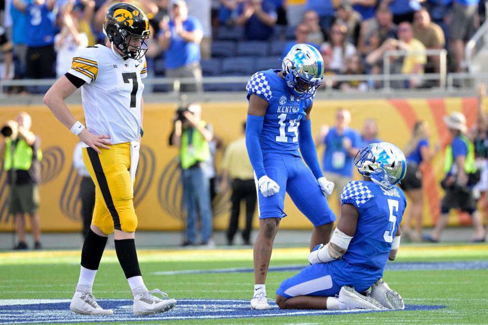 Kentucky defensive back Carrington Valentine (14) and linebacker DeAndre Square (5) celebrate after Square intercepted a pass by Iowa quarterback Spencer Petras (7) to seal the win late in the second half of the Citrus Bowl NCAA college football game, Saturday, Jan. 1, 2022, in Orlando, Fla.