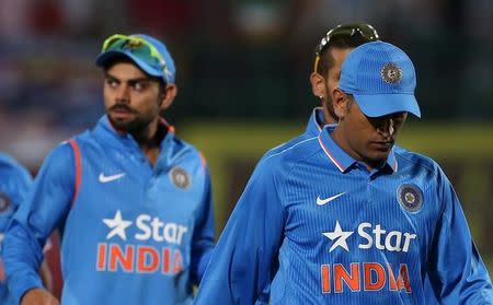 India's captain Mahendra Singh Dhoni (R) and Virat Kohli walk off the ground after losing against South Africa during their first Twenty-20 cricket match in the northern Indian hill town of Dharamsala, India, October 2, 2015. REUTERS/Adnan Abidi