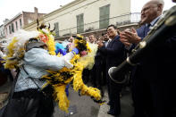 French President Emmanuel Macron, center, claps to music and a costumed dancer as he walks past street musicians on Royal Street in the French Quarter of New Orleans, Friday, Dec. 2, 2022. Right of macron is New Orleans Mayor Latoya Cantrell and former Mayor Mitch Landrieu, right. (AP Photo/Gerald Herbert)