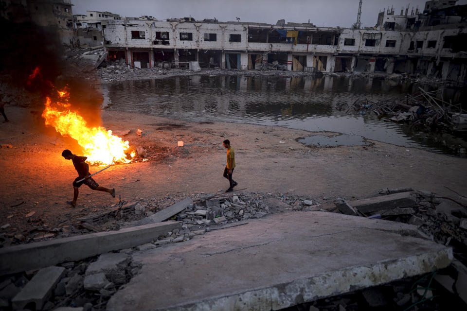 Palestinians displaced by the Israeli air and ground offensive on the Gaza Strip, light a fire to keep away mosquitoes and other insects, which have recently infested the streets of the southern town of Khan Younis, Gaza Strip, Thursday, July 4, 2024. (AP Photo/Jehad Alshrafi)