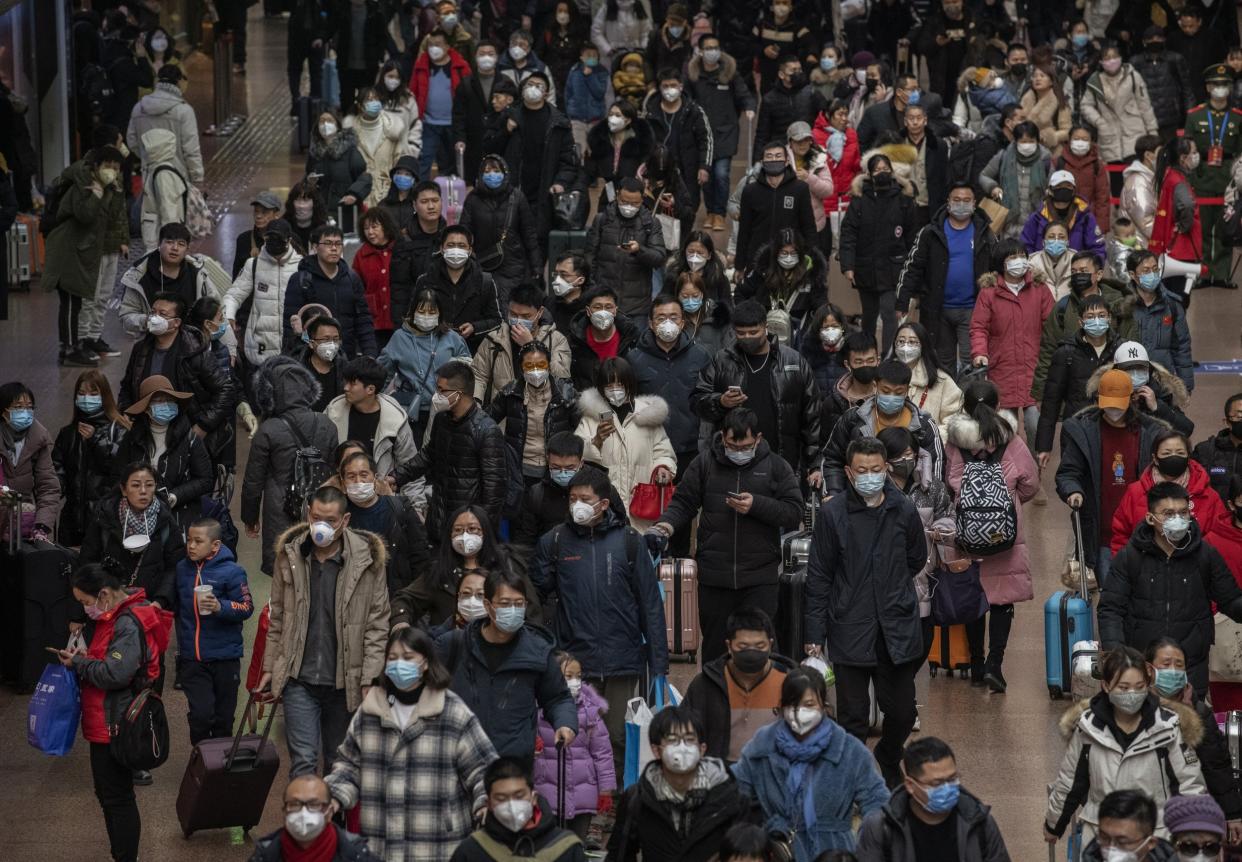 Chinese passengers, most wearing masks, arrive to board trains before the annual spring festival at a Beijing railway station on 23 January 2020: Getty