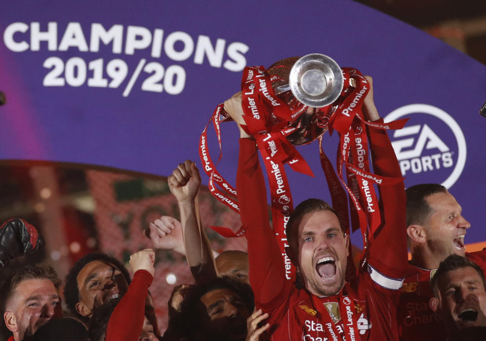 Liverpool's Jordan Henderson, surrounded by his teammates, lifts the English Premier League trophy following the English Premier League soccer match between Liverpool and Chelsea at Anfield Stadium in Liverpool, England, Wednesday, July 22, 2020. Liverpool are champions of the EPL for the season 2019-2020. The trophy is presented at the teams last home game of the season. Liverpool won the match against Chelsea 5-3. (Phil Noble/Pool via AP)