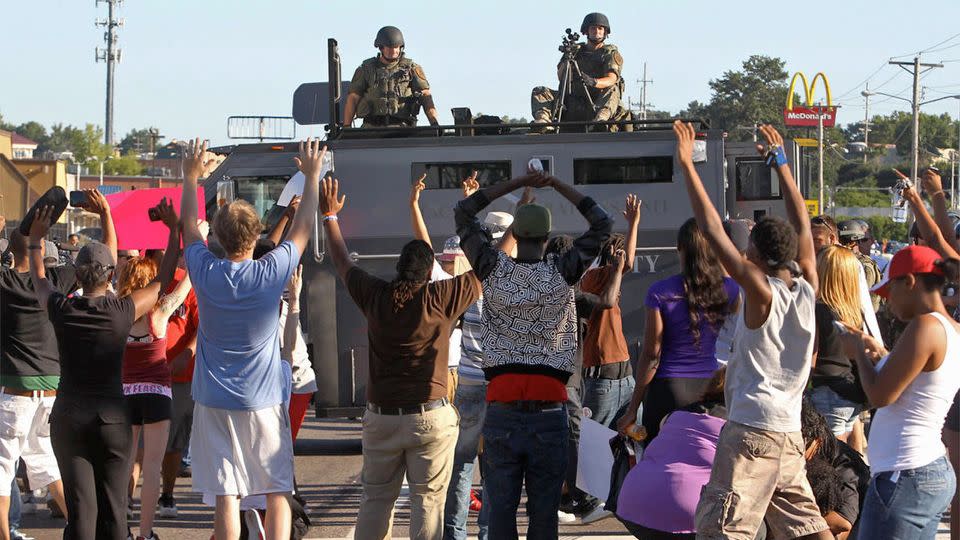 Protesters raise their hands in front of police atop an armoured vehicle in Ferguson, Missouri. Photo: AP.