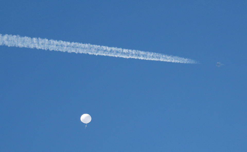 A jet flies by a suspected Chinese spy balloon as it floats off the coast in Surfside Beach, South Carolina, U.S. February 4, 2023.  REUTERS/Randall Hill