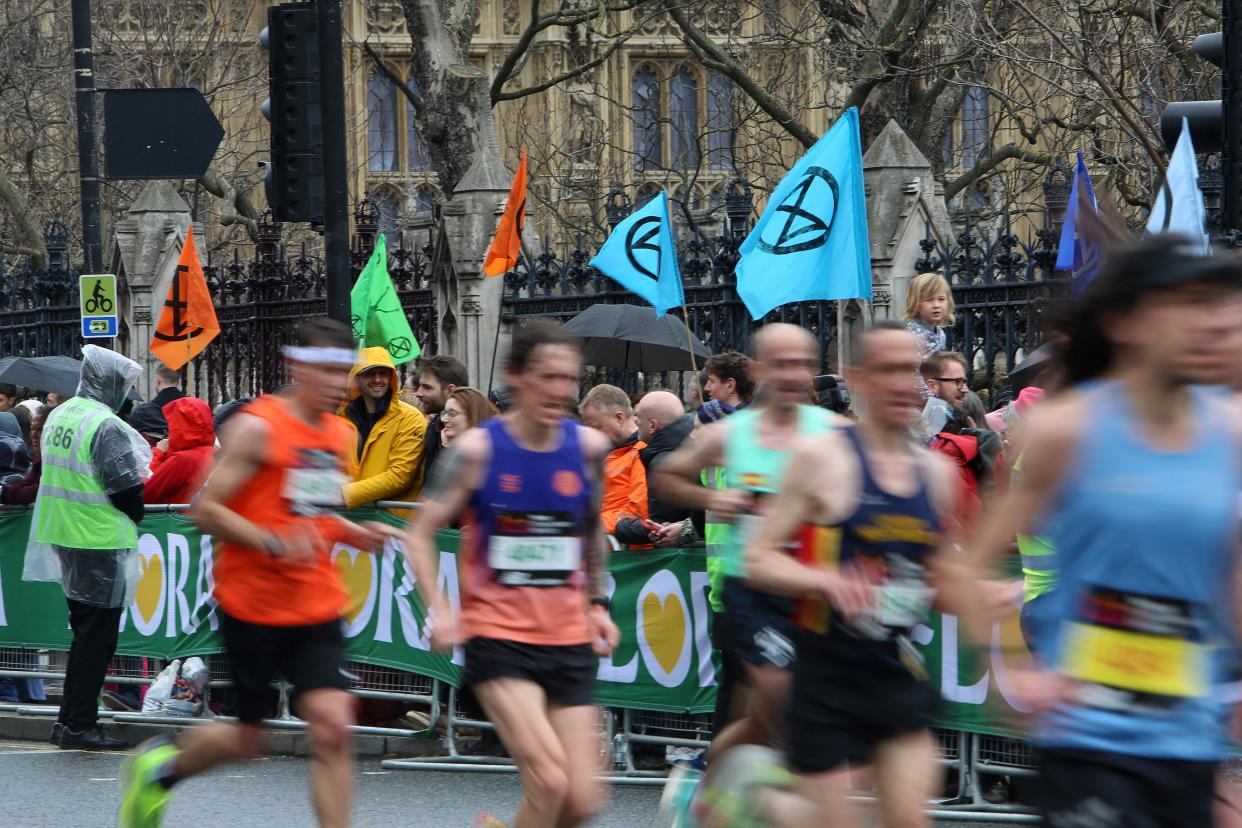 Flags depicting the logo of change protest group Extinction Rebellion are pictured as competitors run past the Palace of Westminster, home of the Houses of Parliament (AFP via Getty Images)