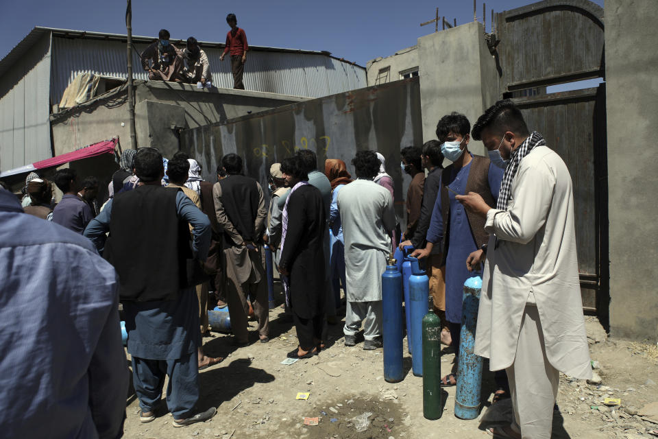 Men wait outside a privately owned oxygen factory to get their oxygen cylinders refilled, in Kabul, Afghanistan, Saturday, June 19, 2021. Health officials say Afghanistan is fast running out of oxygen as a deadly third surge of COVID worsen. (AP Photo/Rahmat Gul)