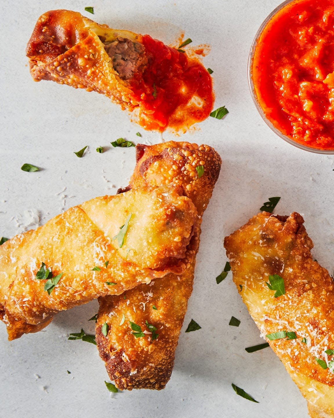 meatball sub egg rolls topped with chopped parsley and marinara