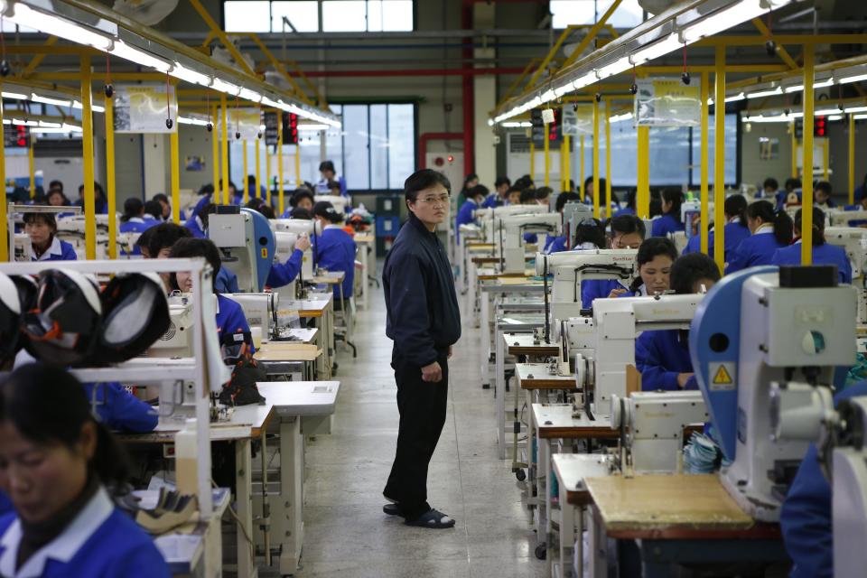 A North Korean manager walks down an aisle as employees work in a factory of a South Korean company at the Joint Industrial Park in Kaesong industrial zone