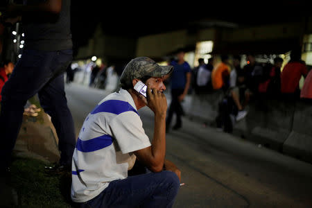 A Honduran uses his phone while waiting to leave with a new caravan of migrants, set to head to the United States, at a bus station in San Pedro Sula, Honduras January 14, 2019. REUTERS/Jorge Cabrera