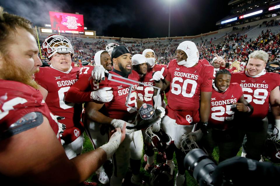 Oklahoma players celebrate with the Bedlam trophy after beating Oklahoma State 28-13 Saturday night in Norman.